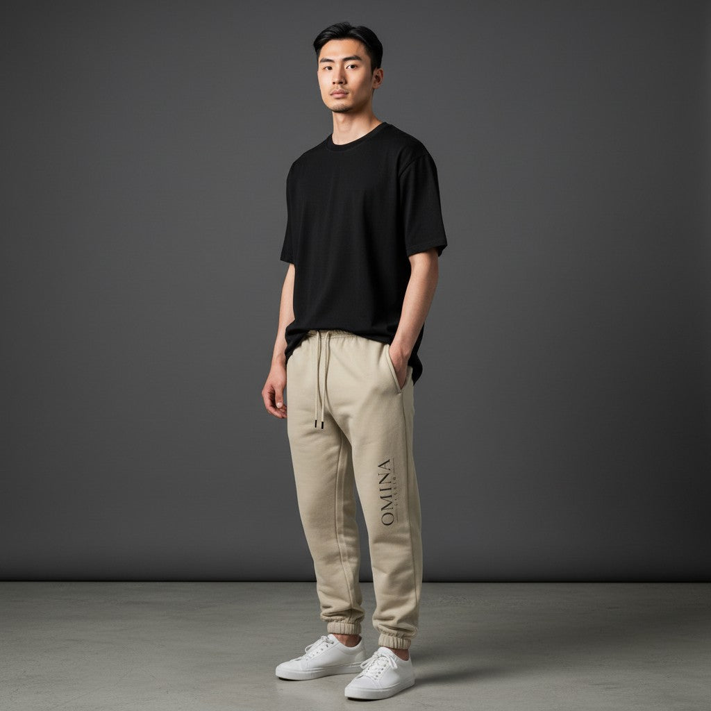 Omina Studio beige heavyweight cotton blend sweatpants with elastic waistband, drawcord, side pockets, and subtle logo.