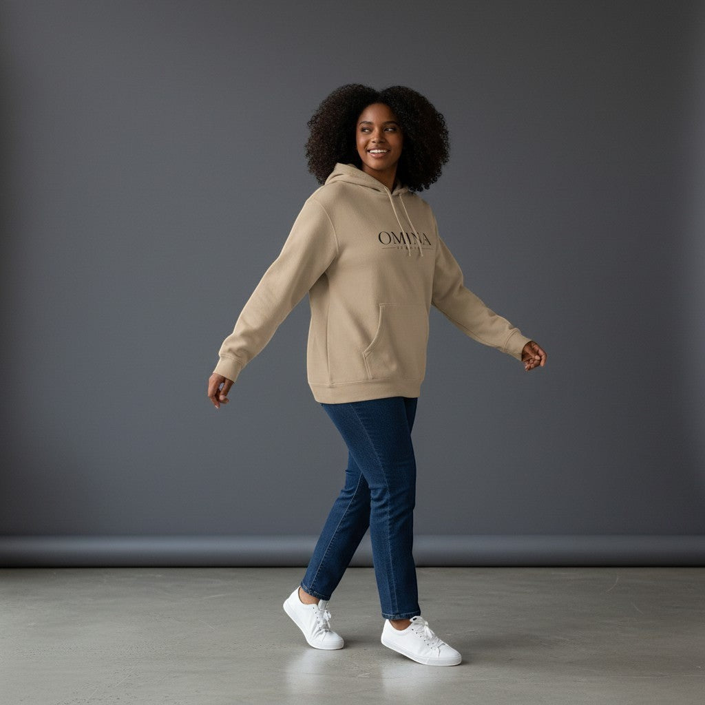 Omina beige pigment-dyed cotton blend hoodie with front logo and relaxed fit, worn by a woman with dark curly hair.