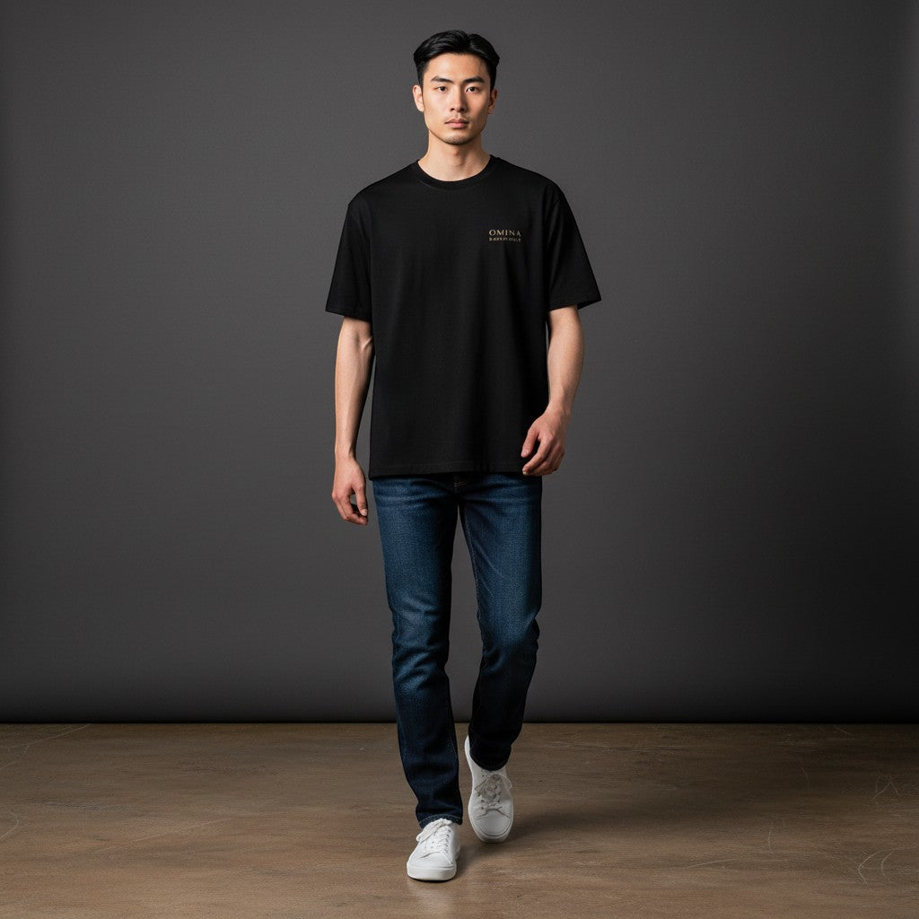 OMINA black premium cotton t-shirt with gold logo detail on chest, worn by a man with jeans.