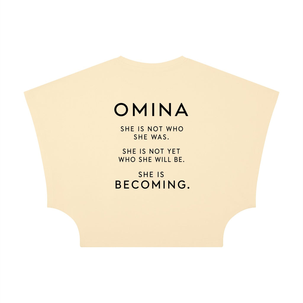 Omina women's cropped dolman t-shirt in light yellow, made of viscose and spandex, with a round neck and short raglan sleeves. Features text: "SHE IS NOT WHO SHE WAS. SHE IS NOT YET WHO SHE WILL BE. SHE IS BECOMING."