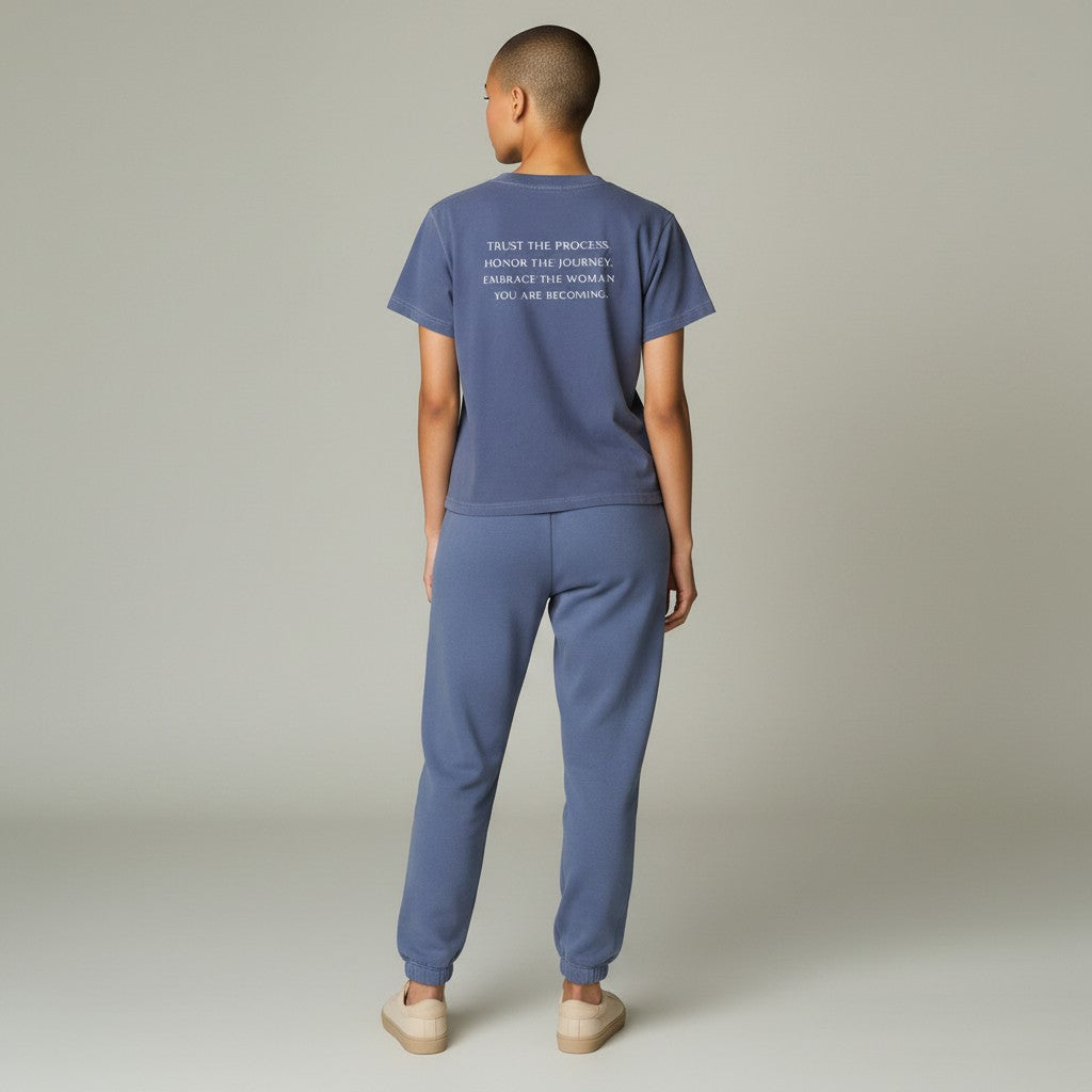 OMINA Essentials blue cotton t-shirt with vintage wash and white text reading "TRUST THE PROCESS. HONOR THE JOURNEY. EMBRACE THE WOMAN YOU ARE BECOMING."