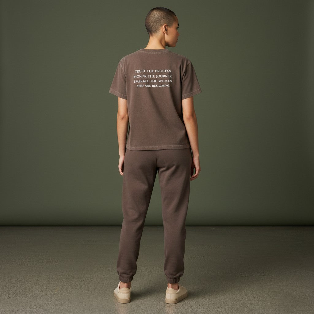 OMINA Essentials brown cotton t-shirt with vintage wash and white text reading "TRUST THE PROCESS. HONOR THE JOURNEY. EMBRACE THE WOMAN YOU ARE BECOMING."