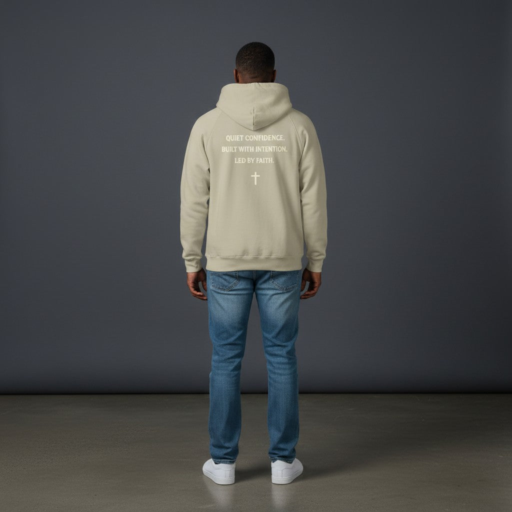 Omina Studio beige heavyweight cotton pullover hoodie with "Quiet Confidence. Built With Intention. Led By Faith." text and a cross graphic.