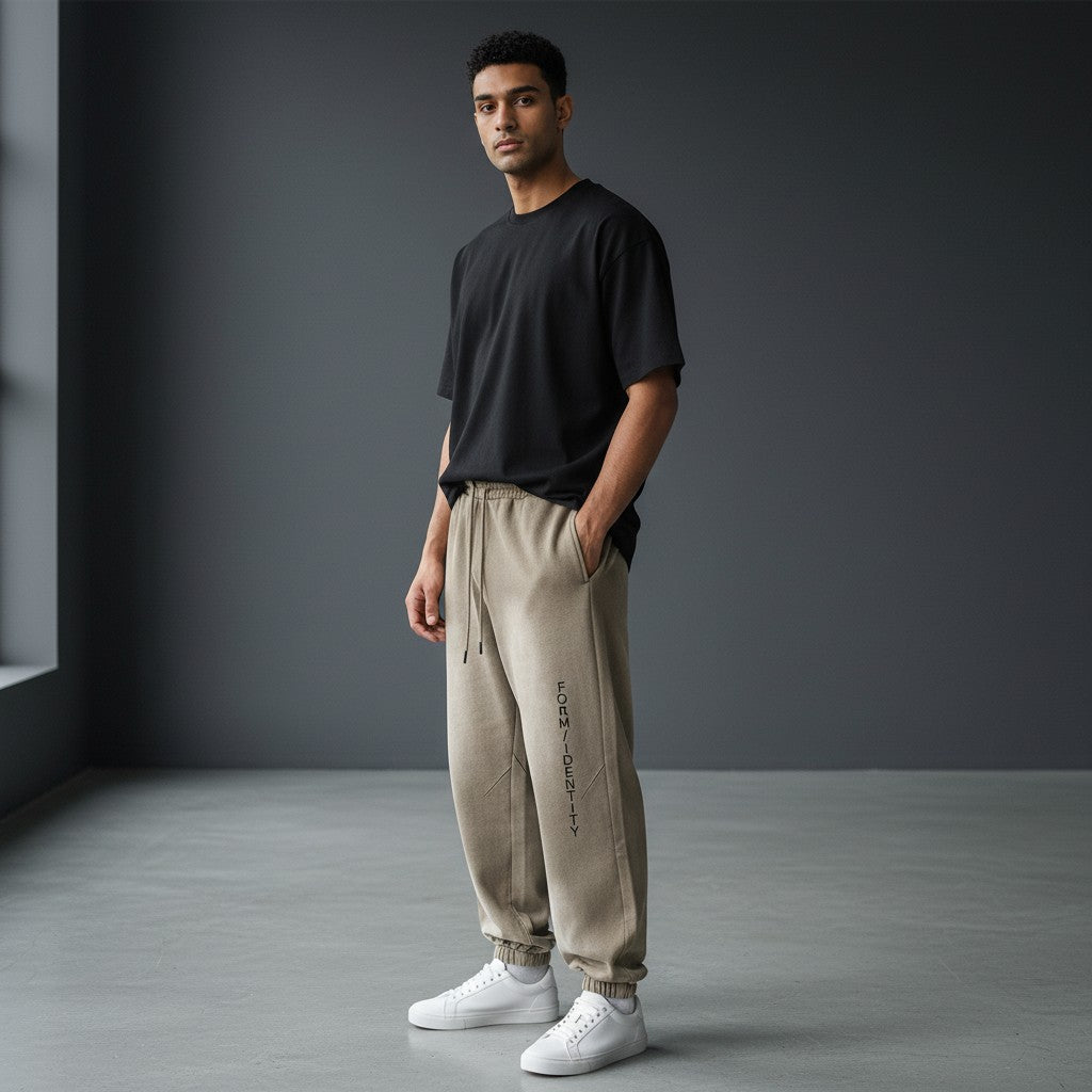 Omina Studio light brown washed cotton sweatpants with relaxed fit and vertical FORM/IDENTITY logo on the left leg.