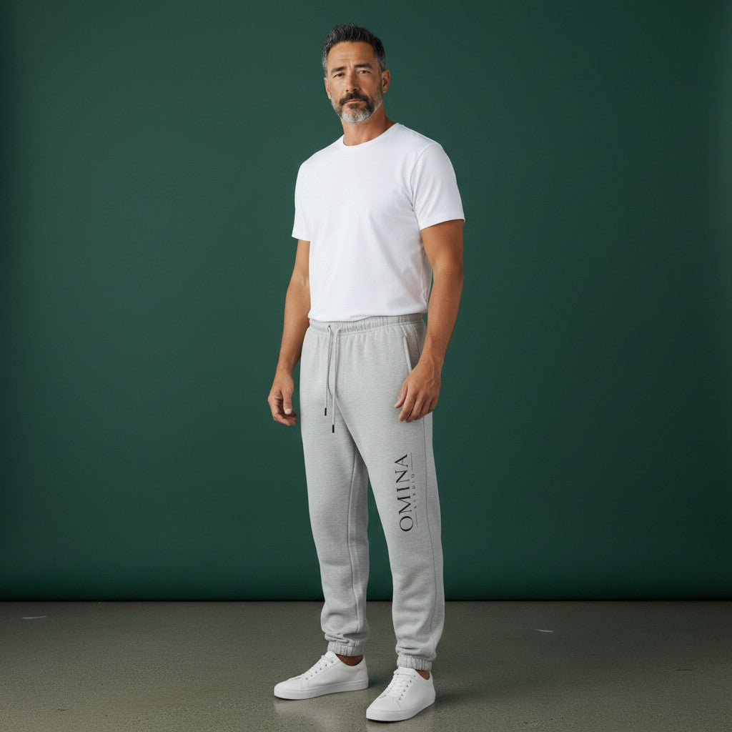Omina Studio light grey heavyweight cotton blend sweatpants with elastic waistband, drawcord, side pockets, and subtle vertical logo.