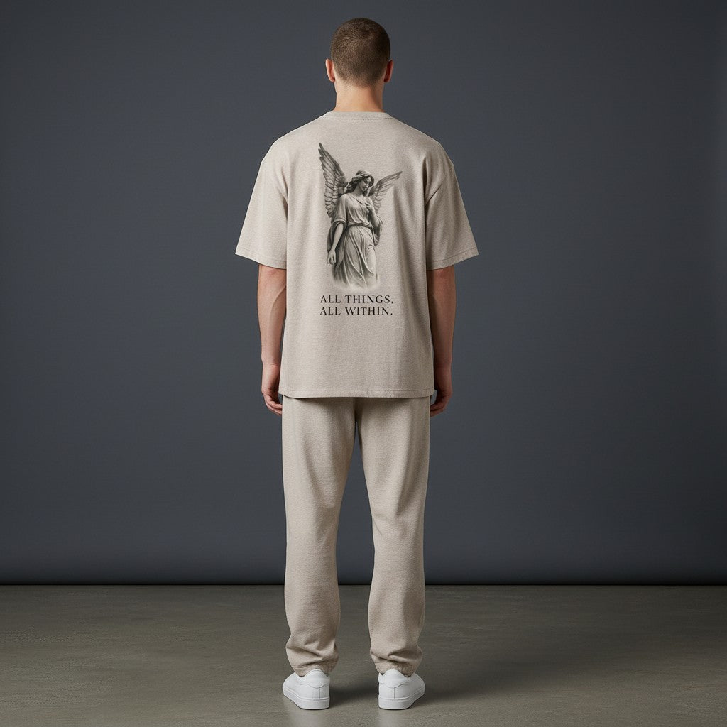 OMINA Studio beige essential cotton t-shirt with angel graphic and "ALL THINGS, ALL WITHIN." text on back.