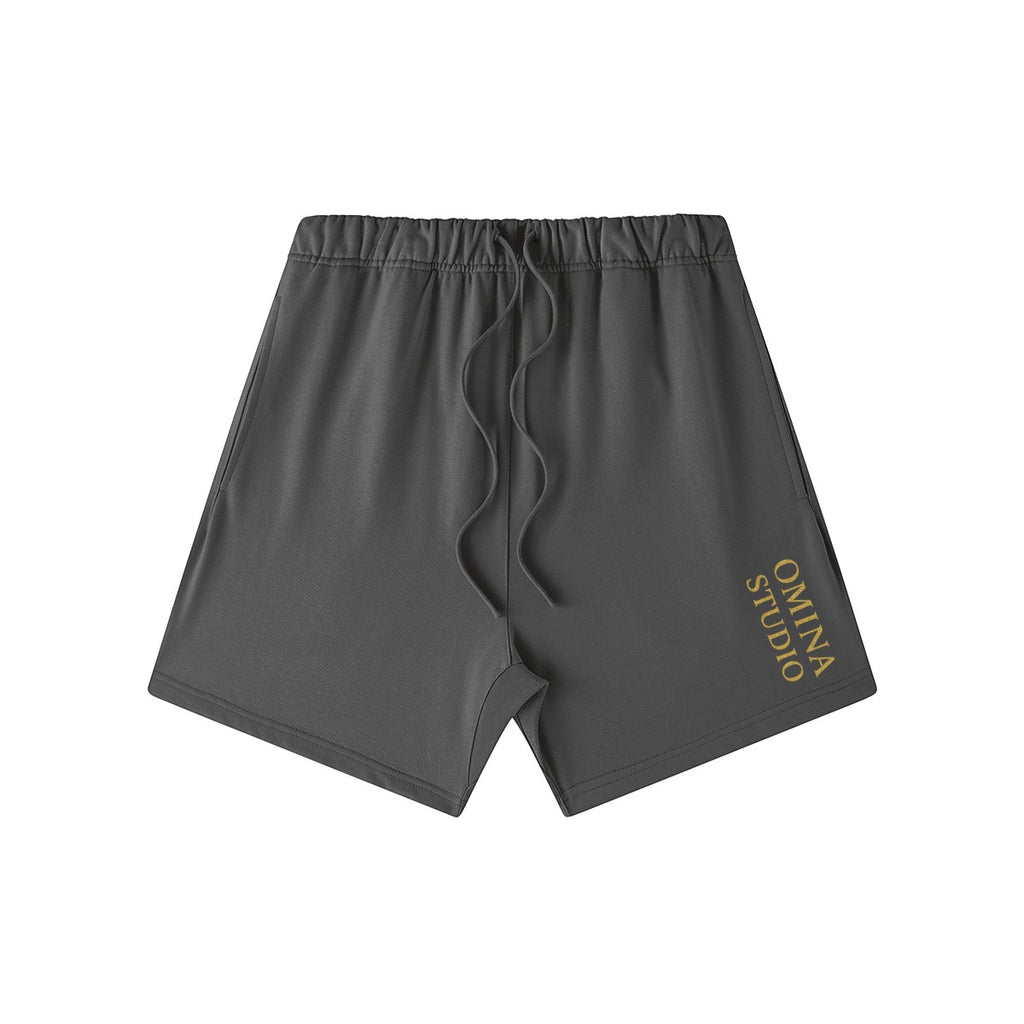 Omina Studio charcoal grey heavyweight French terry cotton shorts with drawstring and gold logo.