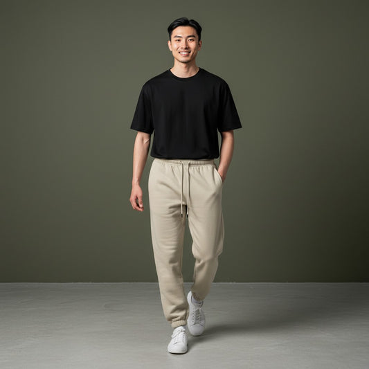 Omina Studio beige 100% combed cotton sweatpants with tapered fit, elastic waistband, drawstring, and cuffed ankles.