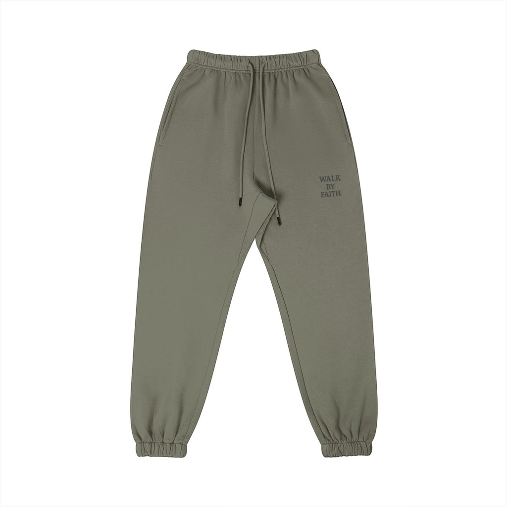 Omina Studio olive green cotton sweatpants with 'Walk By Faith' graphic on left thigh, elastic waistband, and tapered leg.