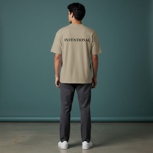 Omina Essentials taupe heavyweight cotton oversized tee with black 'INTENTIONAL' text on the back.
