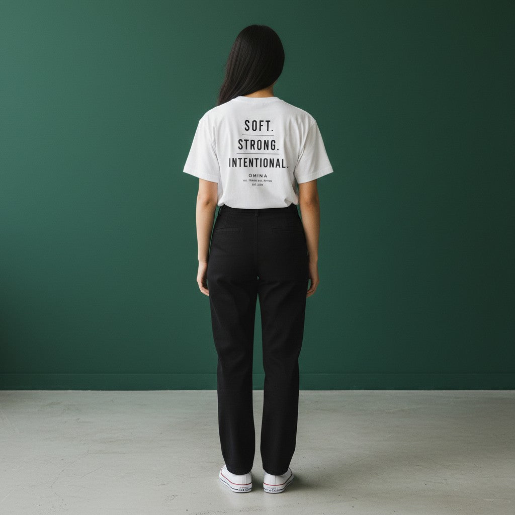 Omina white cotton t-shirt with black text reading SOFT. STRONG. INTENTIONAL. OMINA ALL THINGS ALL WITHIN EST. 2026.