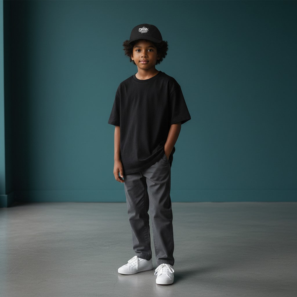 Omina Youth black cotton twill low-profile cap with white graffiti-style logo and adjustable buckle closure.